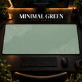 Minimal Green desk mat with pale contour lines on sage green, shown in a warm, dark desk setup.