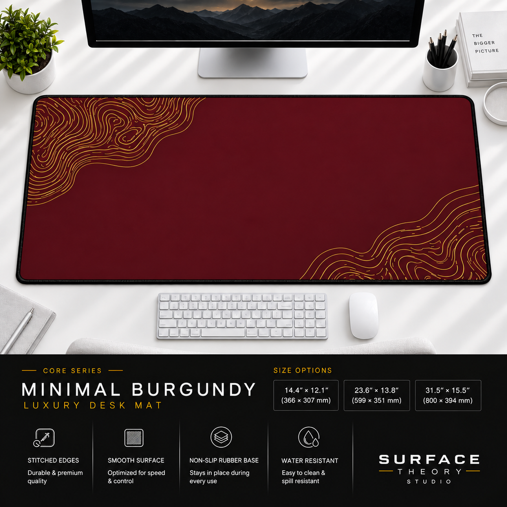 Minimal Burgundy desk mat beneath a monitor on a bright desk with a white keyboard and mouse.