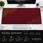 Minimal Burgundy desk mat beneath a monitor on a bright desk with a white keyboard and mouse.