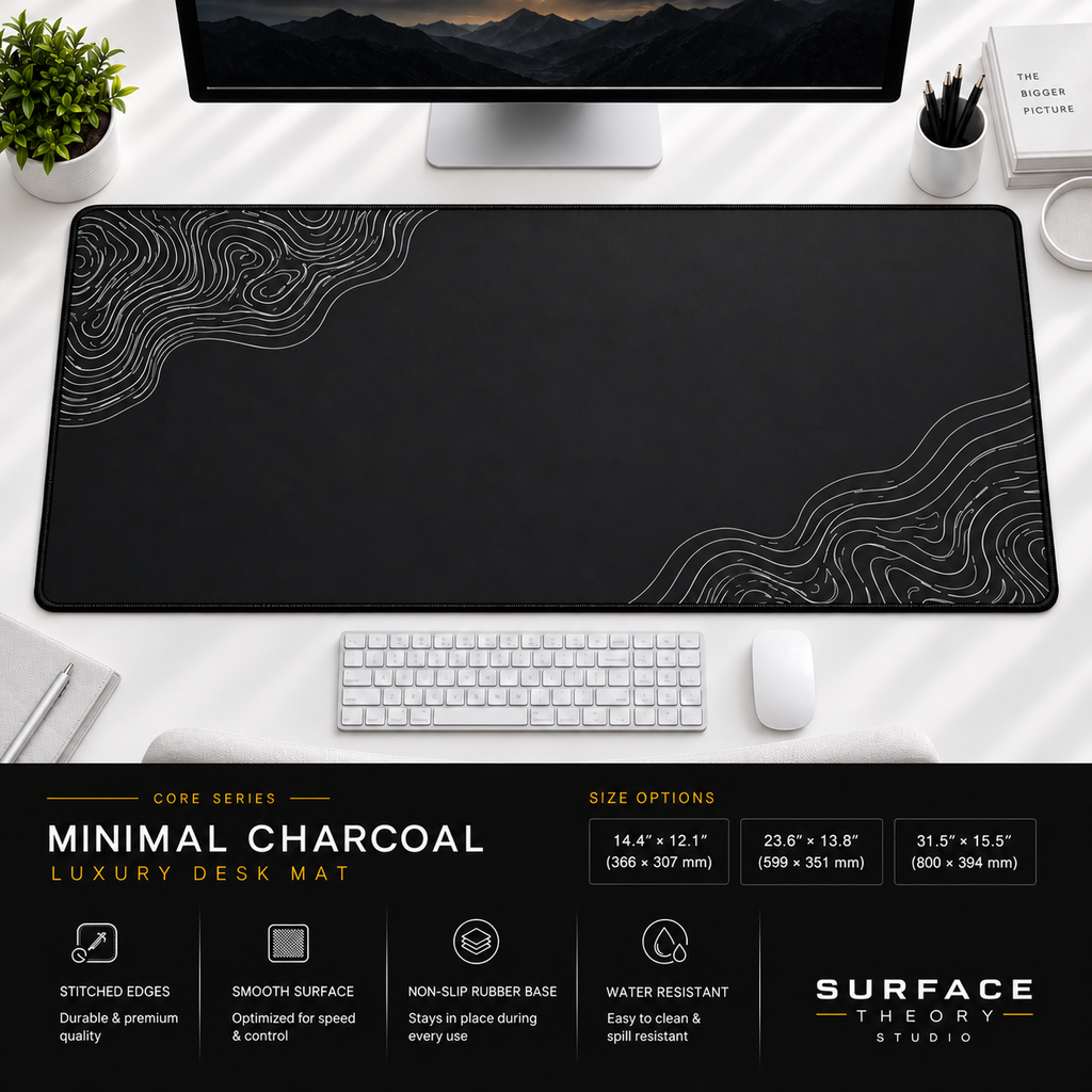 Minimal Charcoal desk mat beneath a monitor on a bright desk with a white keyboard and mouse.