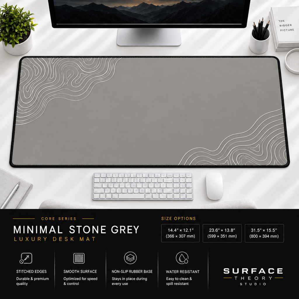Minimal Stone Grey desk mat beneath a monitor on a bright desk with a white keyboard and mouse.