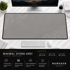Minimal Stone Grey desk mat beneath a monitor on a bright desk with a white keyboard and mouse.