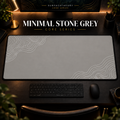 Minimal Stone Grey desk mat with white contour lines on warm grey, shown in a warm, dark desk setup.