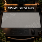 Minimal Stone Grey desk mat with white contour lines on warm grey, shown in a warm, dark desk setup.