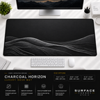 Charcoal Horizon desk mat beneath a monitor on a bright desk with a white keyboard and mouse.