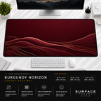 Burgundy Horizon desk mat beneath a monitor on a bright desk with a white keyboard and mouse.