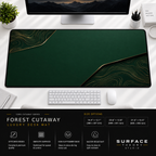Forest Cutaway desk mat beneath a monitor on a bright desk with a white keyboard and mouse.