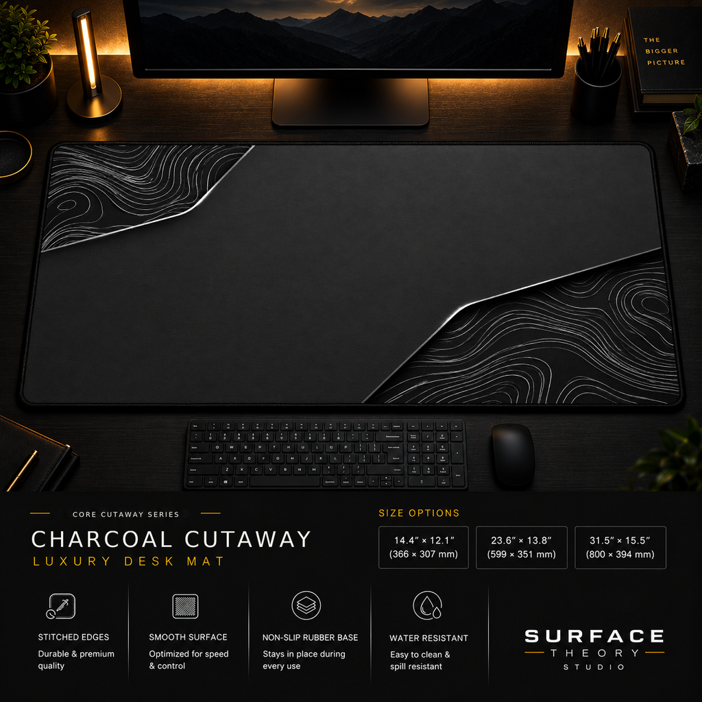 Charcoal Cutaway desk mat in a dark workstation with warm monitor lighting.
