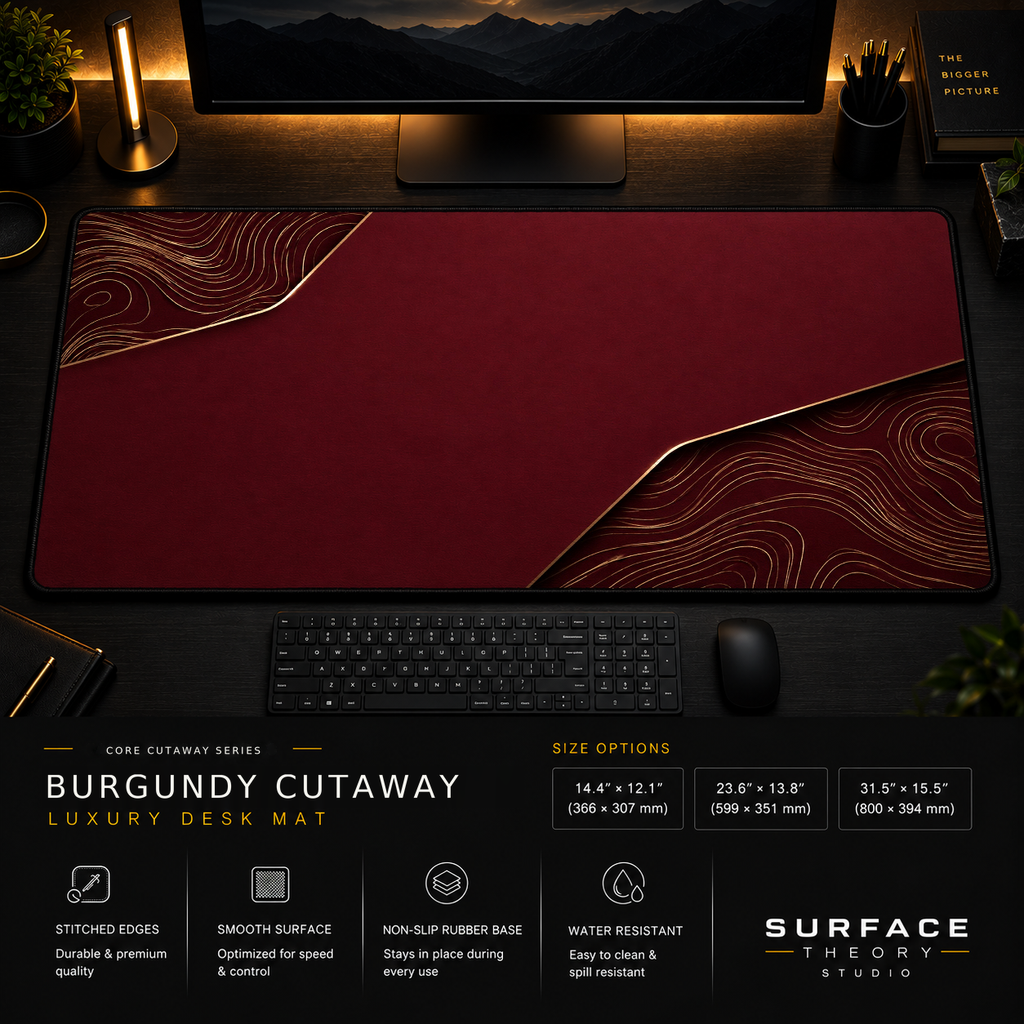 Burgundy Cutaway desk mat in a dark workstation with warm monitor lighting.