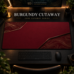 Burgundy Cutaway desk mat, burgundy with gold-toned contours in opposing corners, in a warm, dark workspace.