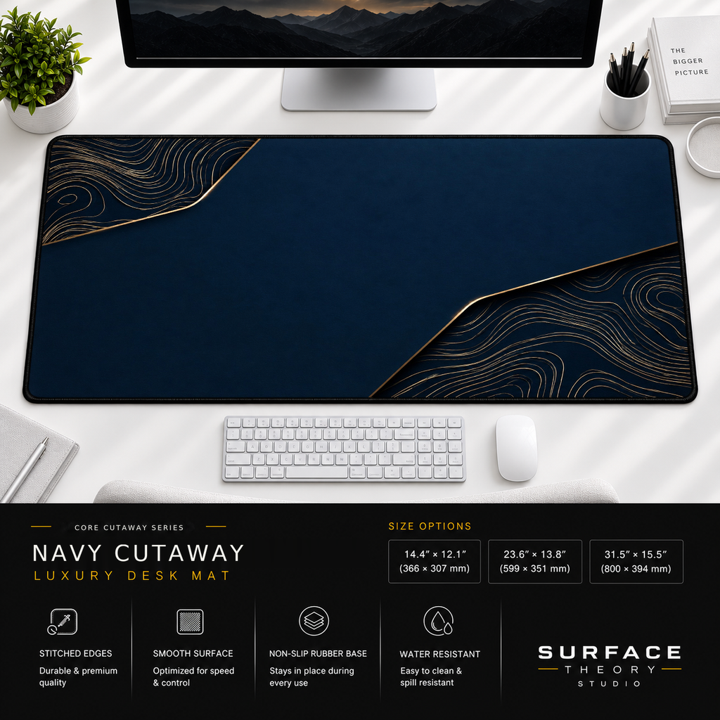 Navy Cutaway desk mat beneath a monitor on a bright desk with a white keyboard and mouse.
