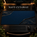 Navy Cutaway desk mat, navy blue with gold-toned contours in opposing corners, in a warm, dark workspace.