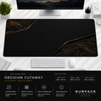 Obsidian Cutaway desk mat beneath a monitor on a bright desk with a white keyboard and mouse.