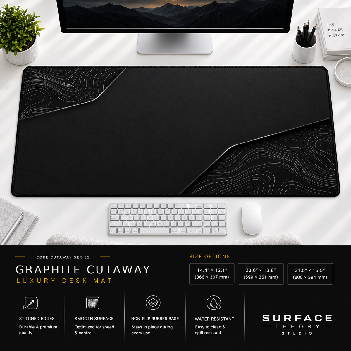 Graphite Cutaway desk mat beneath a monitor on a bright desk with a white keyboard and mouse.