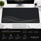 Charcoal Interference desk mat beneath a monitor on a bright desk with a white keyboard and mouse.
