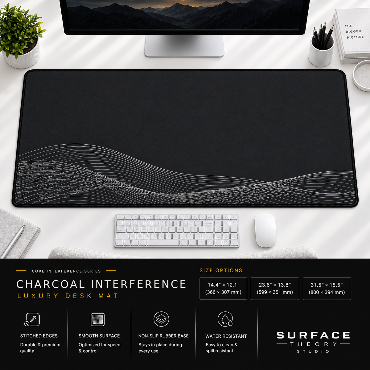 Charcoal Interference desk mat beneath a monitor on a bright desk with a white keyboard and mouse.