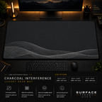 Charcoal Interference desk mat in a dark workstation with warm monitor lighting.