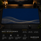 Navy Interference desk mat in a dark workstation with warm monitor lighting.