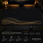 Obsidian Interference desk mat in a dark workstation with warm monitor lighting.