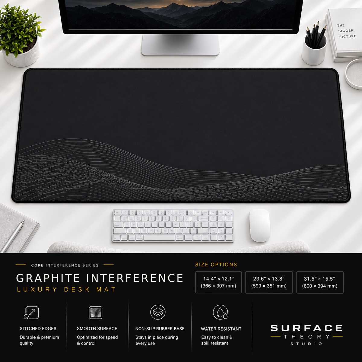 Graphite Interference desk mat beneath a monitor on a bright desk with a white keyboard and mouse.