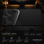 Charcoal Optic desk mat in a dark workstation with warm monitor lighting.
