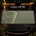 Sage Optic desk mat, muted sage green with pale cream-green contours in a rounded form on the left, in a warm, dark workspace.