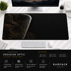 Obsidian Optic desk mat beneath a monitor on a bright desk with a white keyboard and mouse.