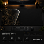 Obsidian Optic desk mat in a dark workstation with warm monitor lighting.