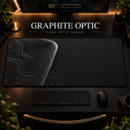 Graphite Optic desk mat, graphite grey with grey contours in a rounded form on the left, in a warm, dark workspace.
