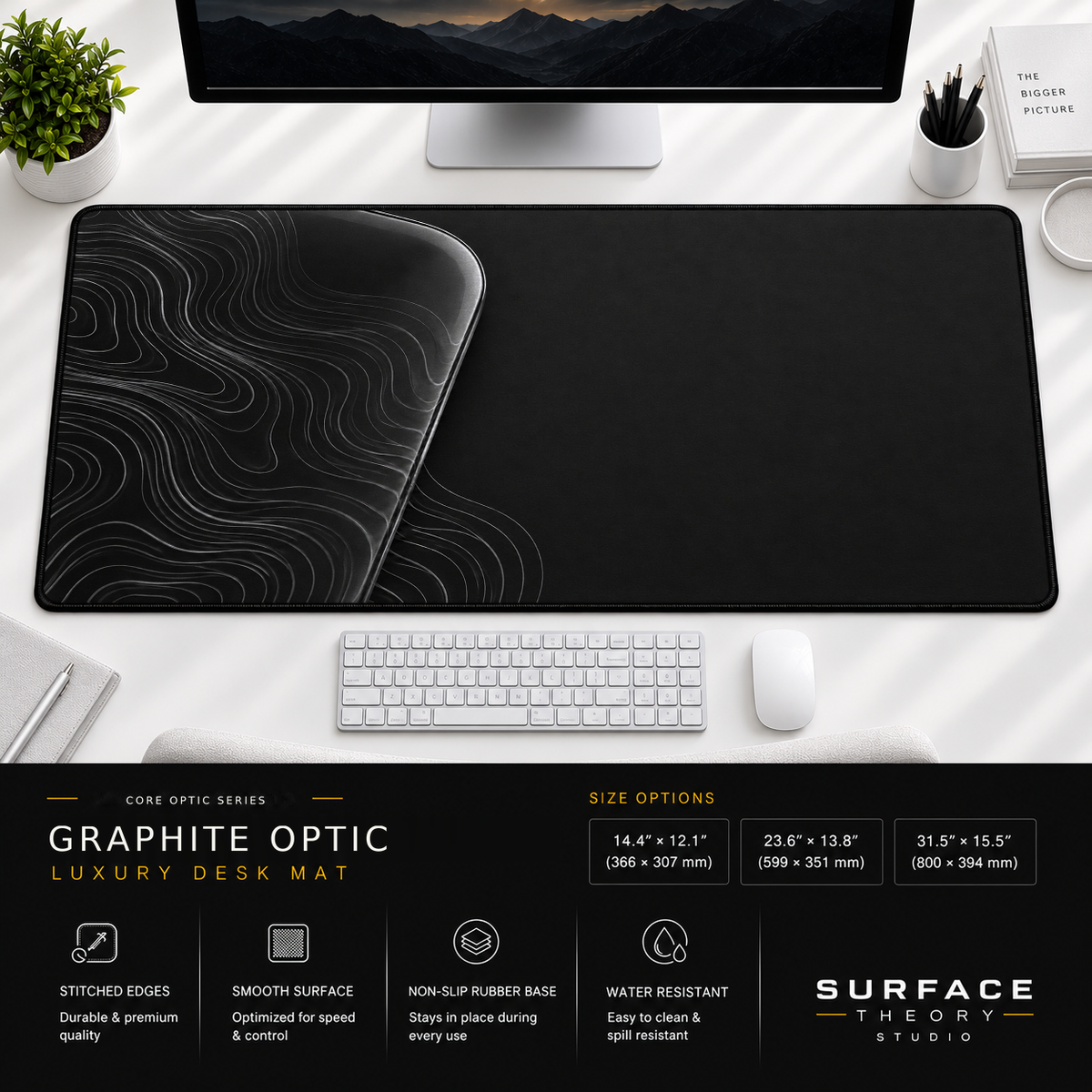Graphite Optic desk mat beneath a monitor on a bright desk with a white keyboard and mouse.