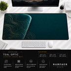 Teal Optic desk mat beneath a monitor on a bright desk with a white keyboard and mouse.