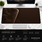Espresso Optic desk mat beneath a monitor on a bright desk with a white keyboard and mouse.