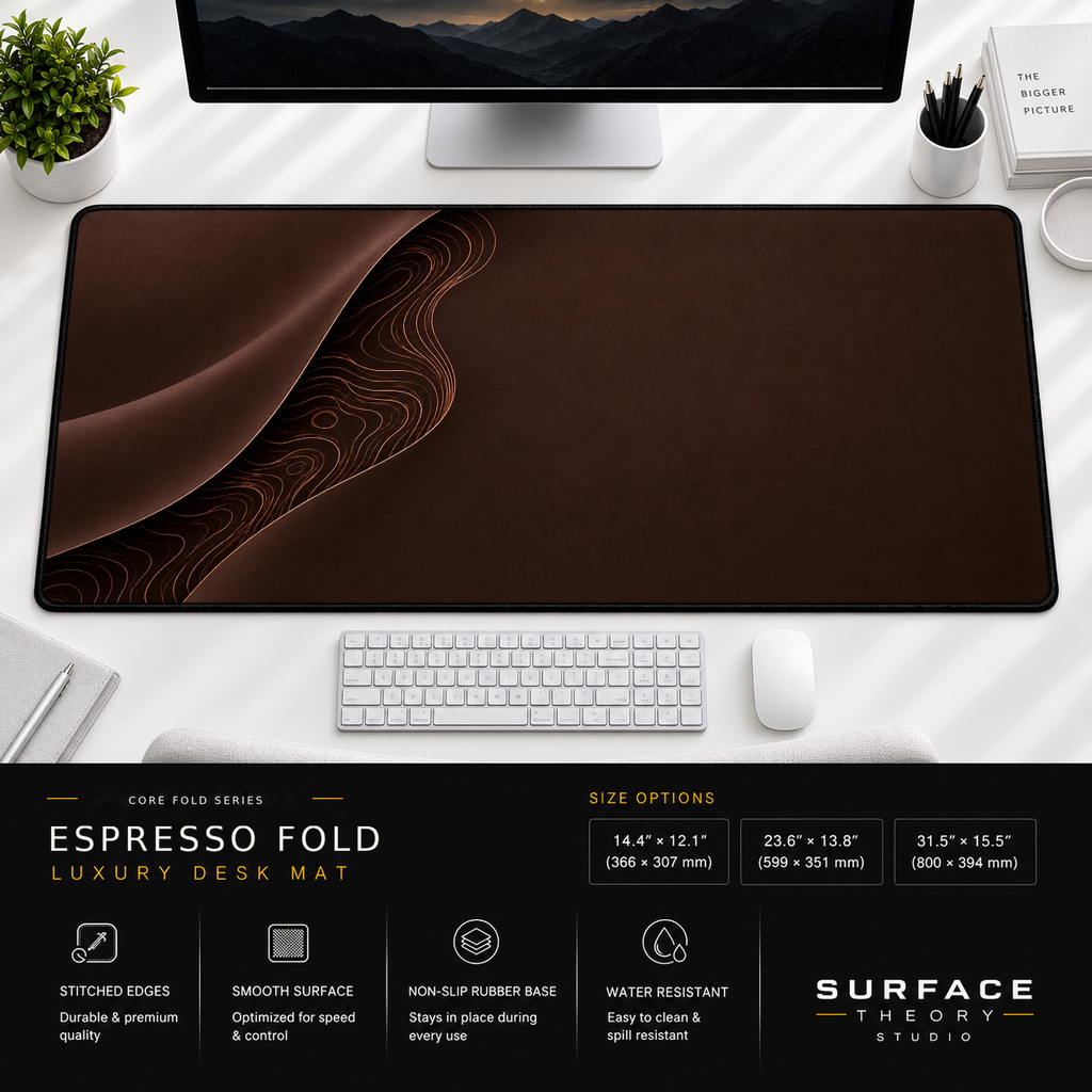 Espresso Fold desk mat beneath a monitor on a bright desk with a white keyboard and mouse.