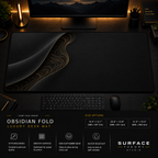 Obsidian Fold desk mat in a dark workstation with warm monitor lighting.