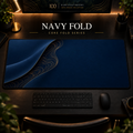 Navy Fold desk mat with a sweeping curve and fine contours along the left in a warm, dark workspace.