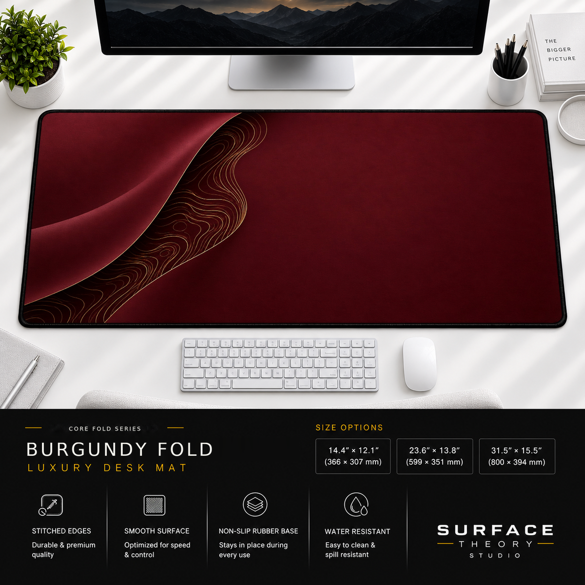 Burgundy Fold desk mat beneath a monitor on a bright desk with a white keyboard and mouse.