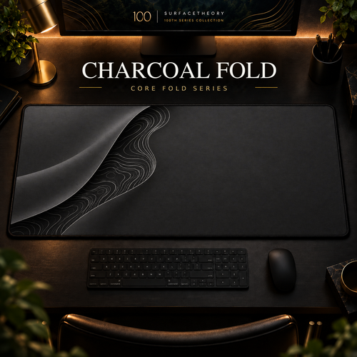 Charcoal Fold desk mat with a sweeping curve and fine contours along the left in a warm, dark workspace.