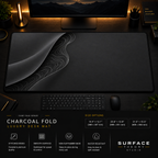 Charcoal Fold desk mat in a dark workstation with warm monitor lighting.