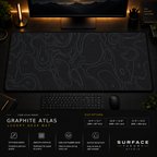 Graphite Atlas desk mat in a dark workstation with warm monitor lighting.