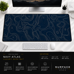Navy Atlas desk mat beneath a monitor on a bright desk with a white keyboard and mouse.