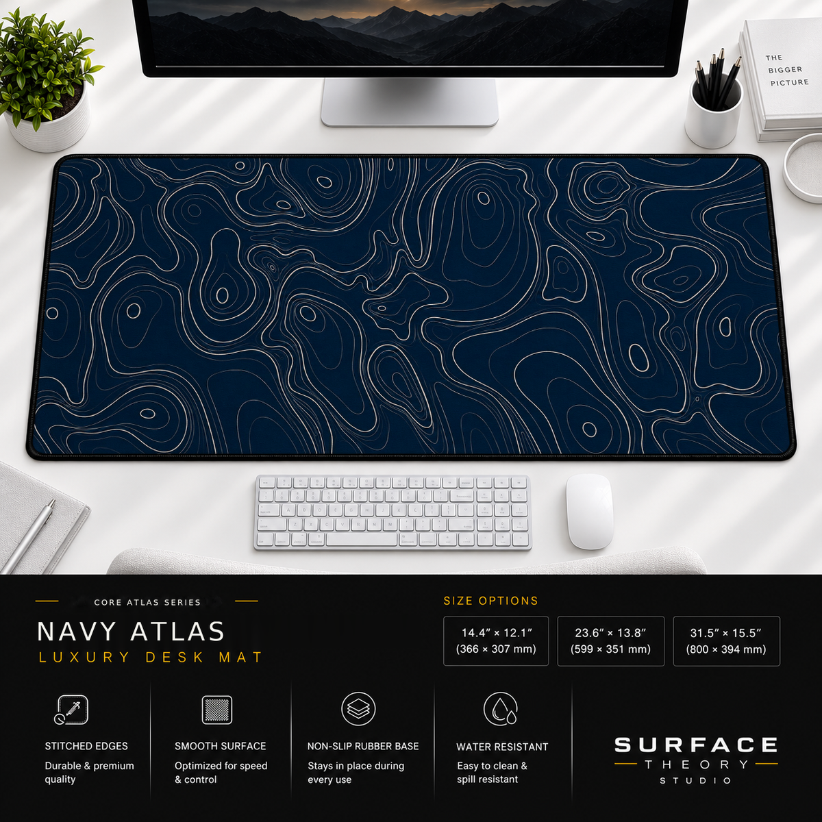 Navy Atlas desk mat beneath a monitor on a bright desk with a white keyboard and mouse.