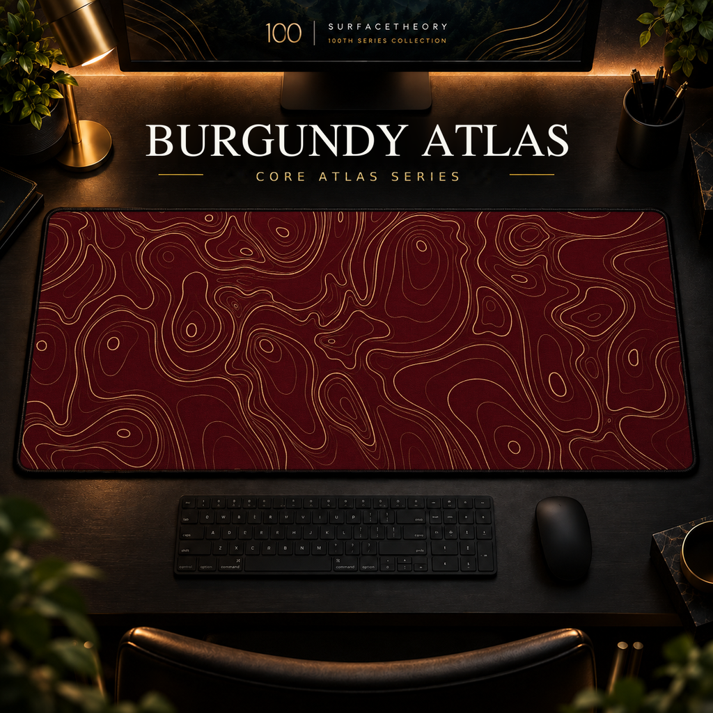 Burgundy Atlas desk mat with fine topographic-inspired contours across the full surface in a warm, dark workspace.