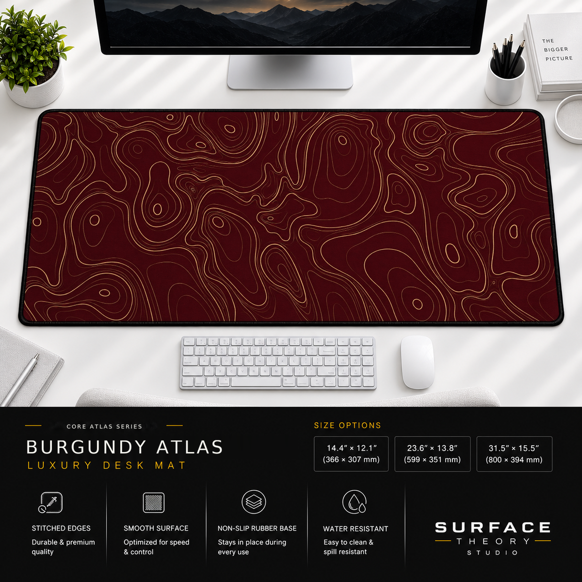 Burgundy Atlas desk mat beneath a monitor on a bright desk with a white keyboard and mouse.