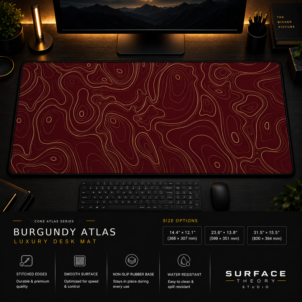 Burgundy Atlas desk mat in a dark workstation with warm monitor lighting.