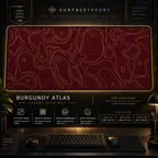 Burgundy Atlas desk mat in a gold-toned showcase frame above a keyboard.