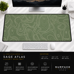 Sage Atlas desk mat beneath a monitor on a bright desk with a white keyboard and mouse.