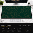 Forest Atlas desk mat beneath a monitor on a bright desk with a white keyboard and mouse.