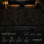 Obsidian Atlas desk mat in a dark workstation with warm monitor lighting.