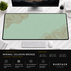 Minimal Celadon Bronze desk mat beneath a monitor on a bright desk with a white keyboard and mouse.