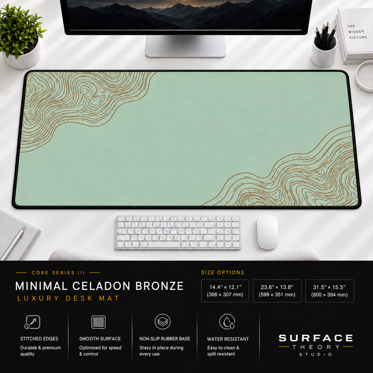 Minimal Celadon Bronze desk mat beneath a monitor on a bright desk with a white keyboard and mouse.